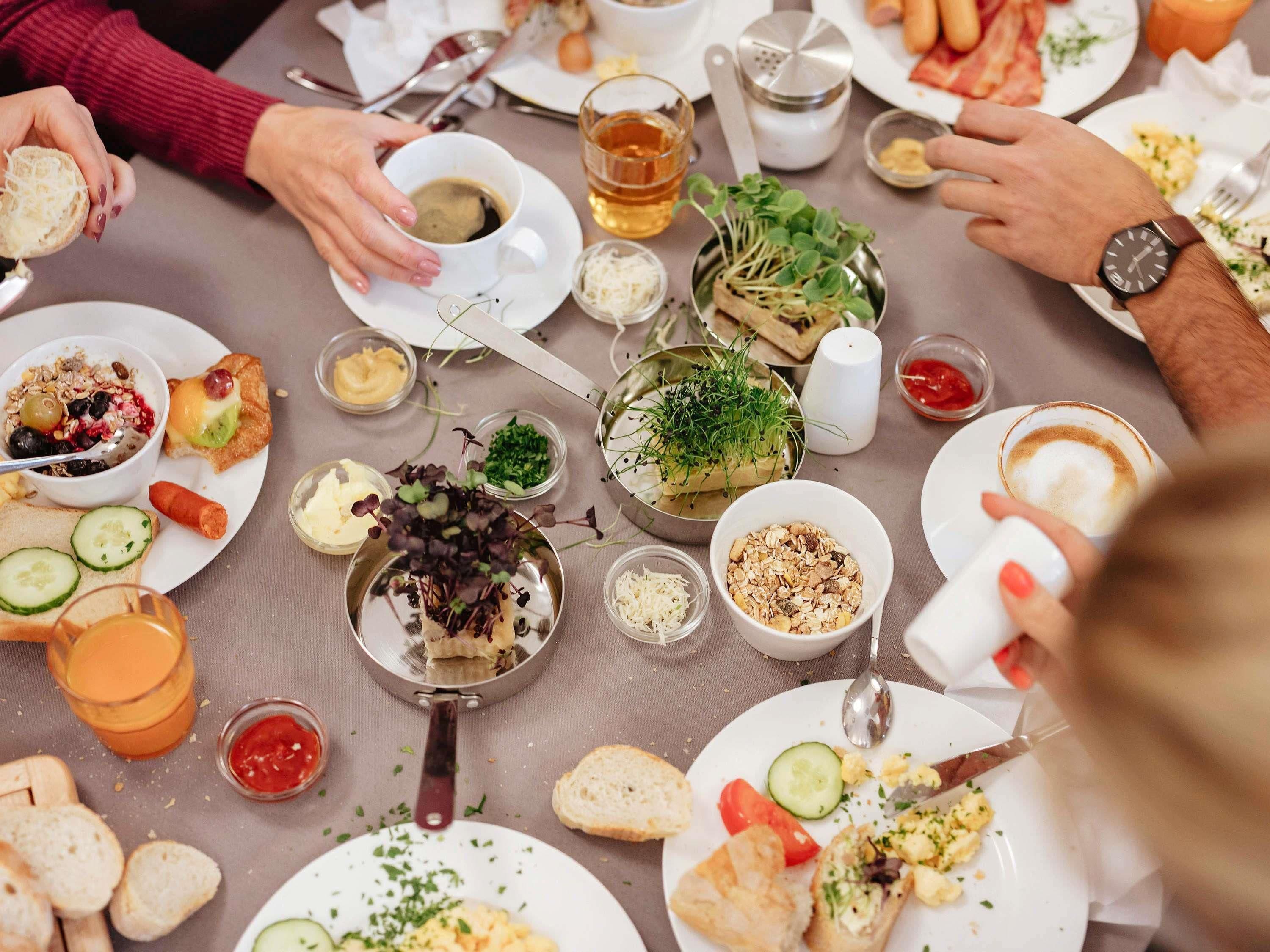 A dining table with various dishes, utensils, and condiments.