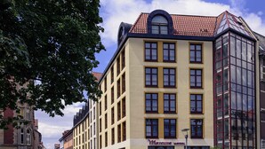 Un hotel con fachada amarilla, múltiples ventanas y tejado de tejas rojas.