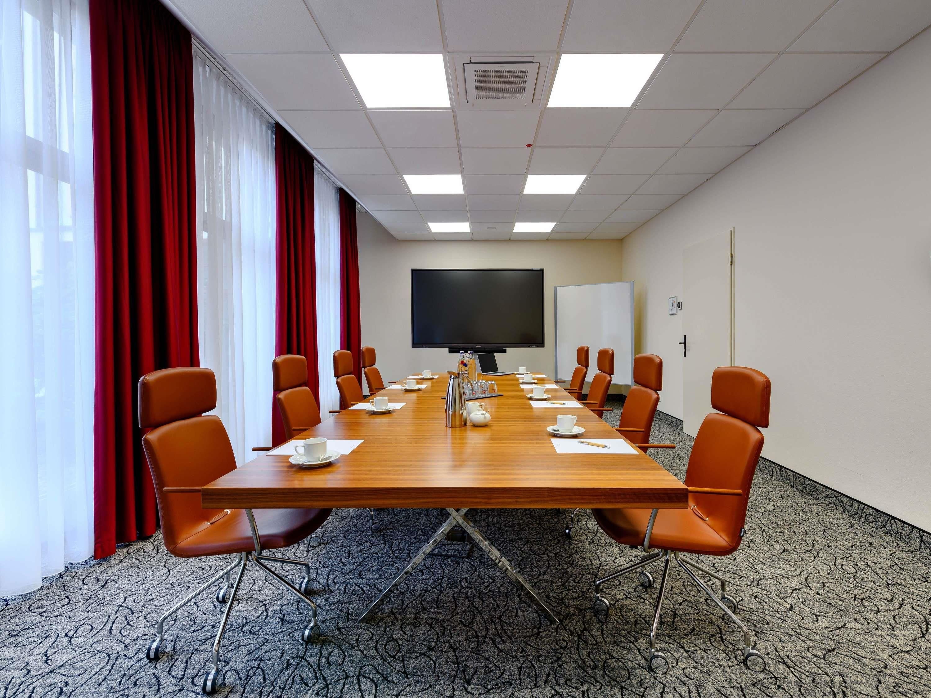 A conference room with a long table, chairs, a projector screen, and a whiteboard.
