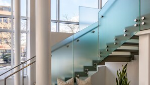 A modern staircase with glass railings, a bench with patterned cushions, and pendant lighting.