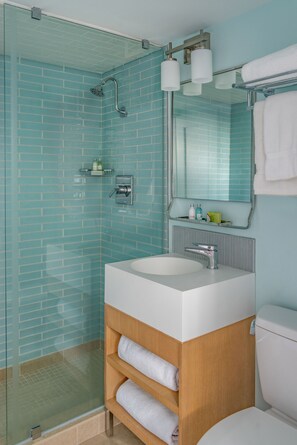 A bathroom with a glass-enclosed shower, a white sink, and a wooden vanity.