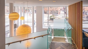 Un intérieur moderne avec une balustrade en verre, un lambris en bois et un parquet disposé en chevrons.