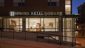 The Harvard Hotel Square building facade at night with illuminated signage.