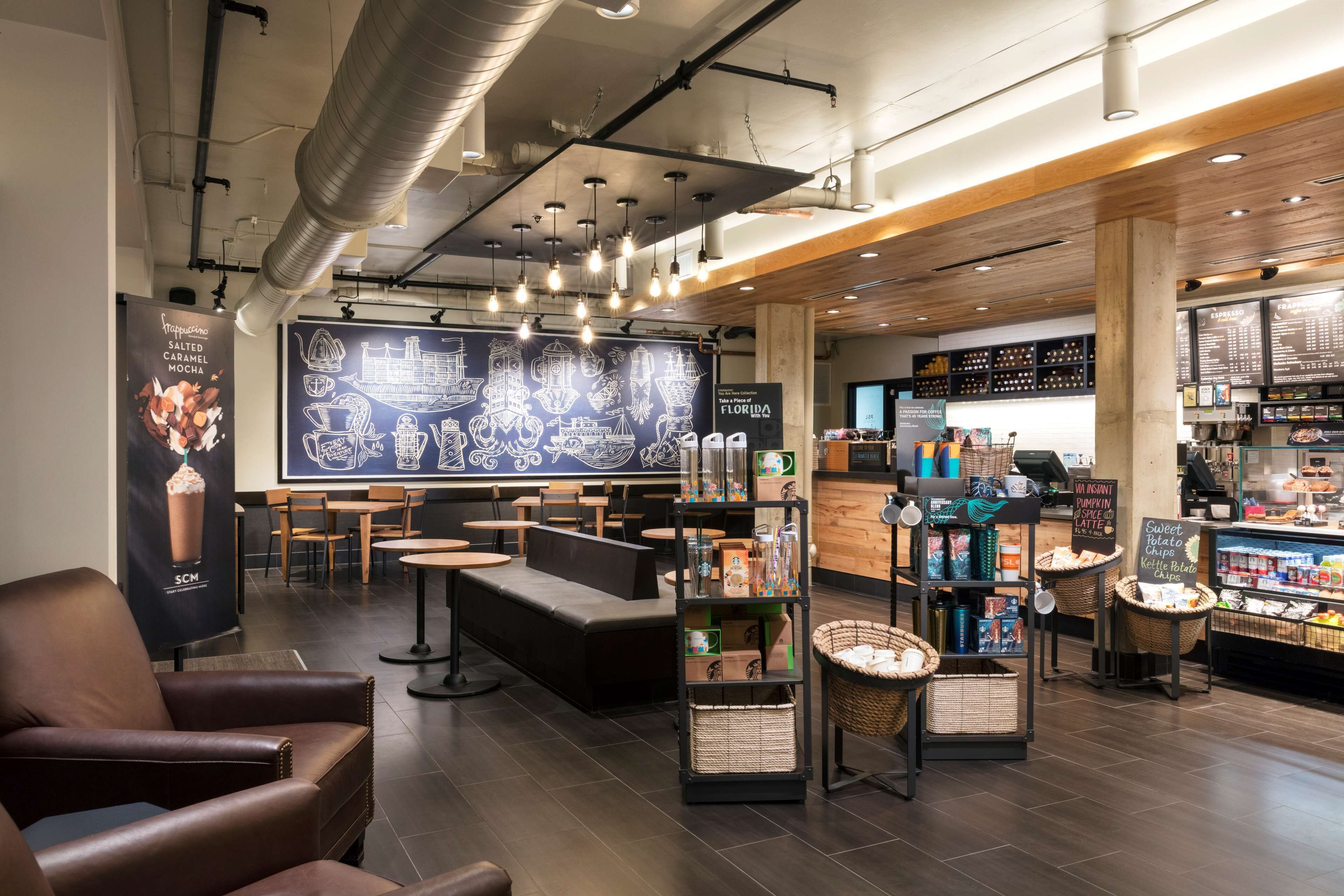 A coffee shop interior with seating, a chalkboard menu, and a display of coffee products.