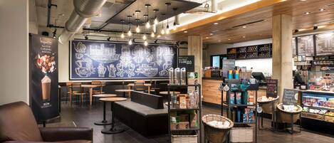 A coffee shop interior with seating, a chalkboard menu, and a display of coffee products.