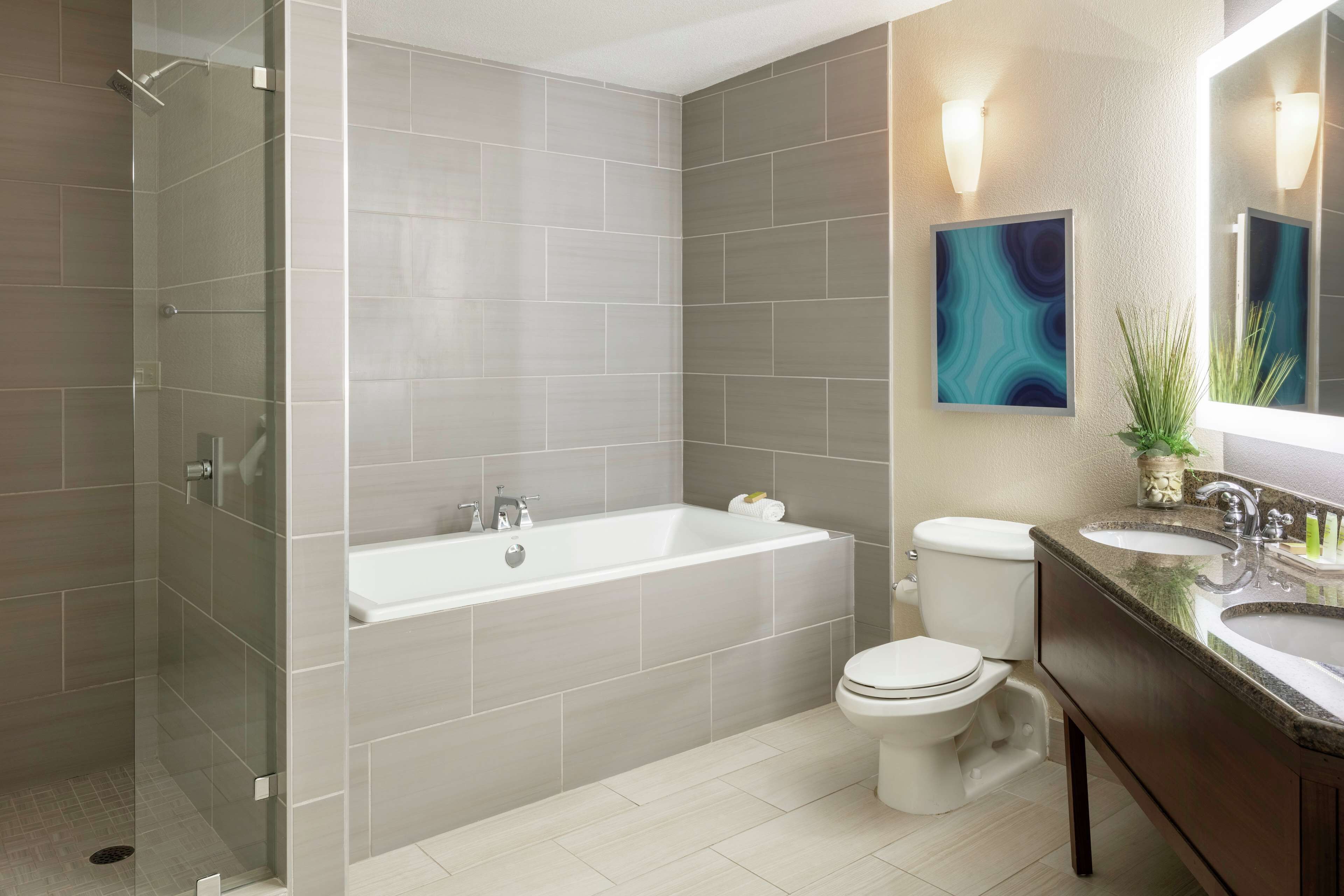 Une salle de bain moderne dotée d’une douche à parois de verre, d’une baignoire sur pieds, de toilettes et d’un meuble-lavabo avec deux vasques.