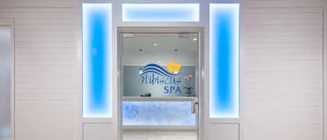 Ein Empfangsbereich mit Glastür, einem Schild mit der Aufschrift 'Hibiscus SPA' und Holzboden.