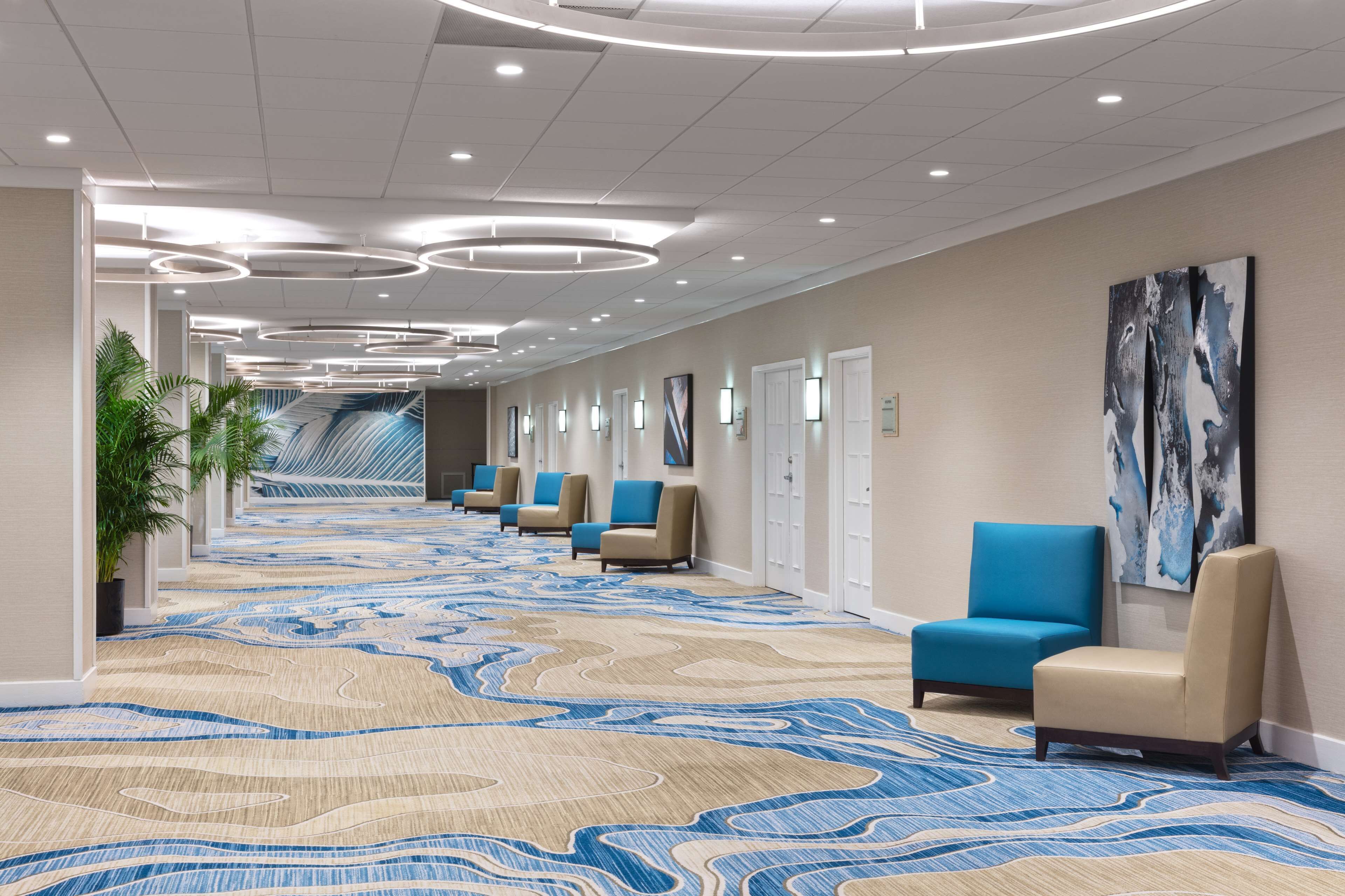 A hotel lobby with a patterned carpet, seating area, and modern lighting.
