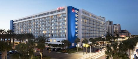 Een groot, meerhoog hotel met een opvallende blauw-witte gevel, met het Hilton logo.