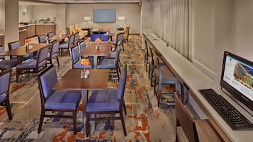 A hotel room with a large dining area, a kitchen, and a computer desk.