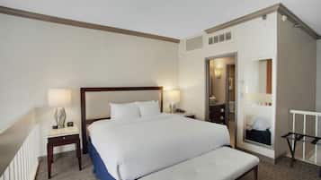 Une chambre d’hôtel avec un grand lit, des tables de chevet, un miroir et un petit banc.