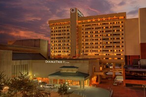 A large hotel with multiple floors, a prominent sign at the top, and a well-lit entrance area. - DoubleTree by Hilton Little Rock (Little Rock)