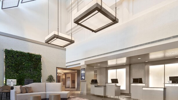 A spacious lobby with a reception desk, seating area, and a green wall. - The Westin Tysons Corner (Falls Church)