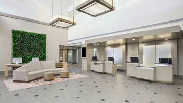 Un hall amplio con una pared verde, un sofá y una mesa de recepción.