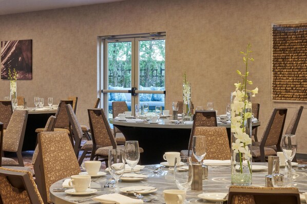 A dining area with round tables, chairs, and floral centerpieces.