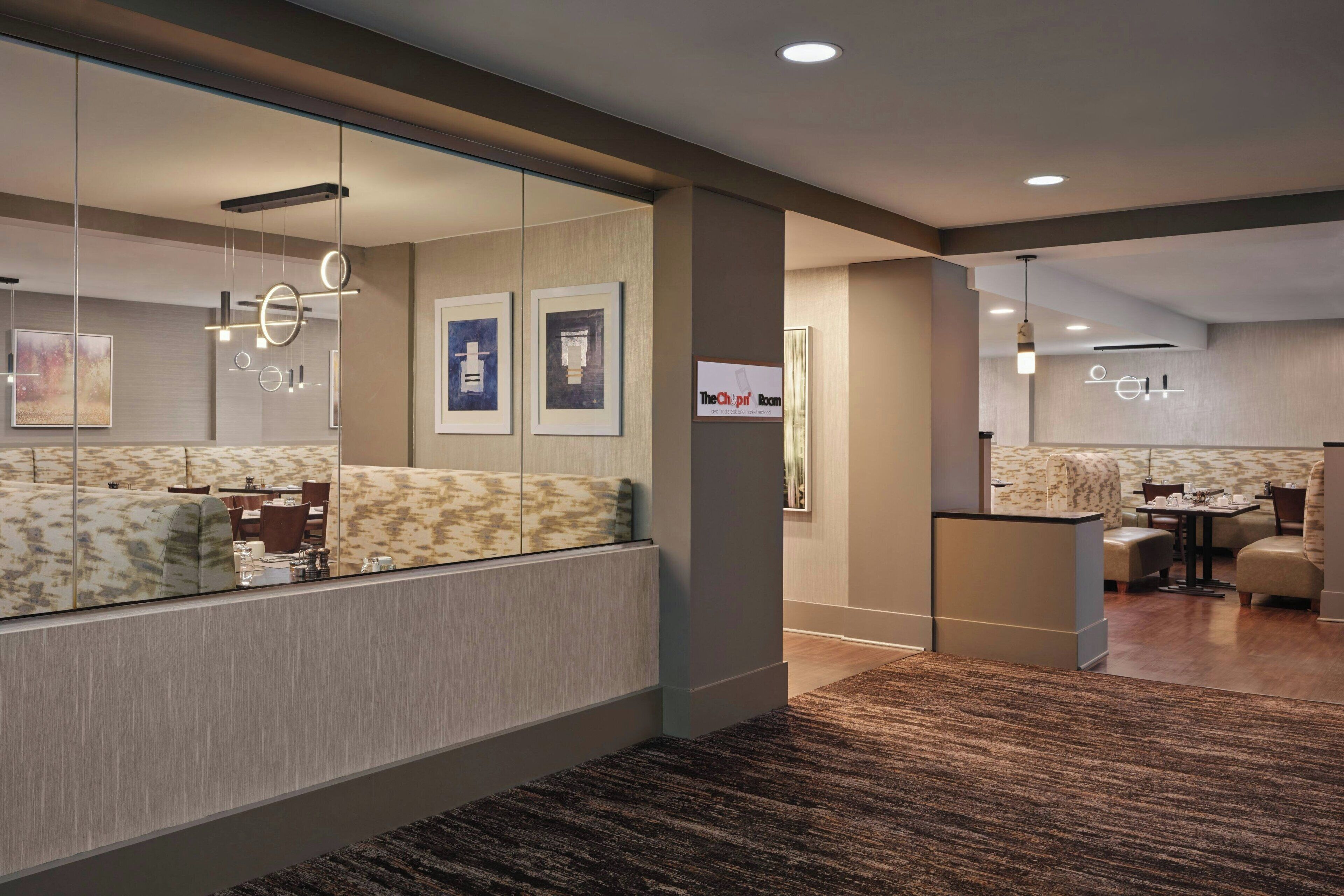 A modern hotel lobby with a reception desk, seating area, and artwork on the walls.