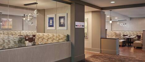 A modern hotel lobby with a reception desk, seating area, and artwork on the walls.