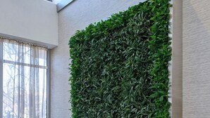 A modern office space with a long white desk, two chairs, and a wall-mounted green plant. - The Westin Tysons Corner (Falls Church)
