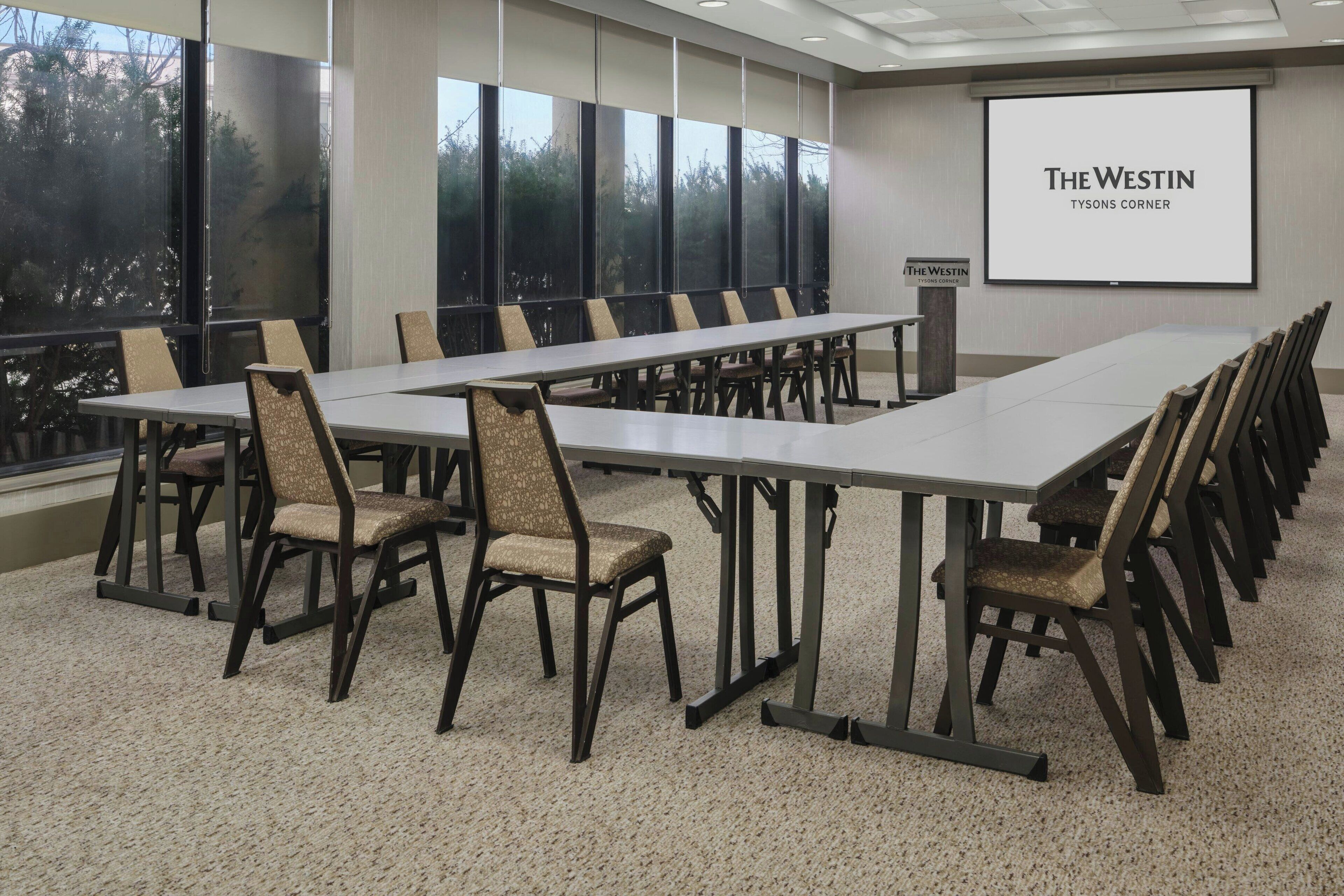 A conference room with a long table and chairs, large windows, and a projection screen displaying 'The Westin Tysons Corner'.