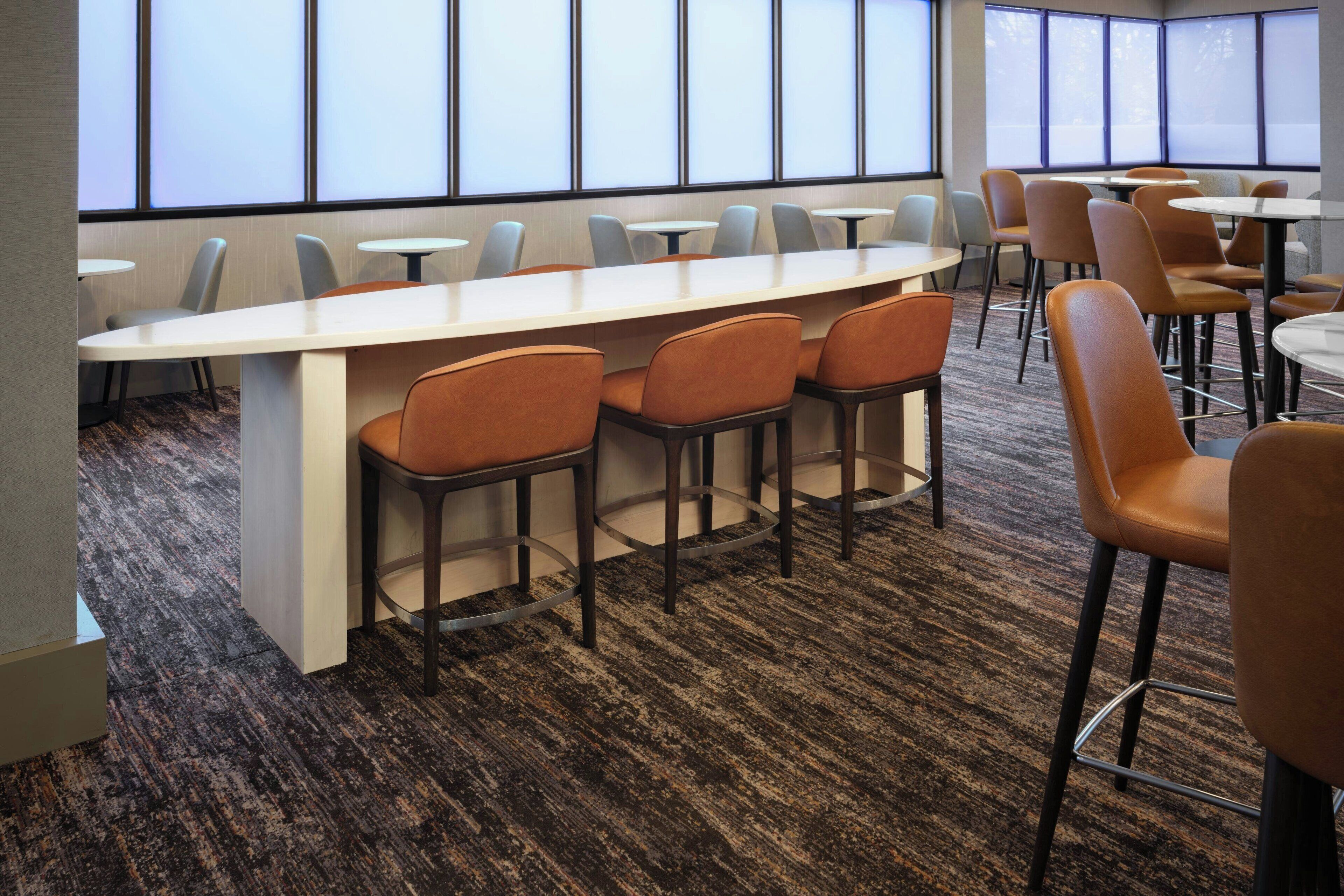 A conference room with a long table and multiple chairs, carpeted floor, and large windows.