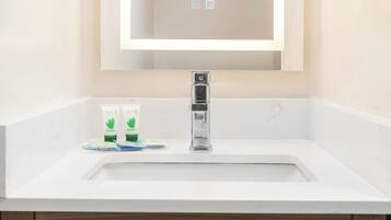 A bathroom with a white sink, a mirror, and a wooden cabinet below.