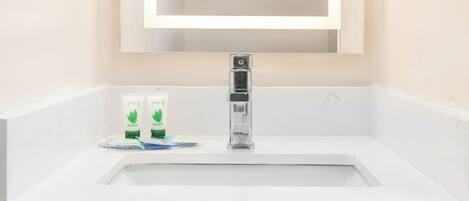 A bathroom with a white sink, a mirror, and a wooden cabinet below.