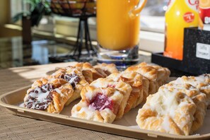 A tray of pastries with a glass of orange juice and a bottle of orange juice on a table.