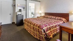 A hotel room with a bed, a desk, a dresser, and a mirror. - Monterey Fairgrounds Inn (Monterey)