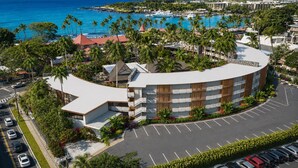 A hotel with a curved building, a parking lot, and a view of the ocean.