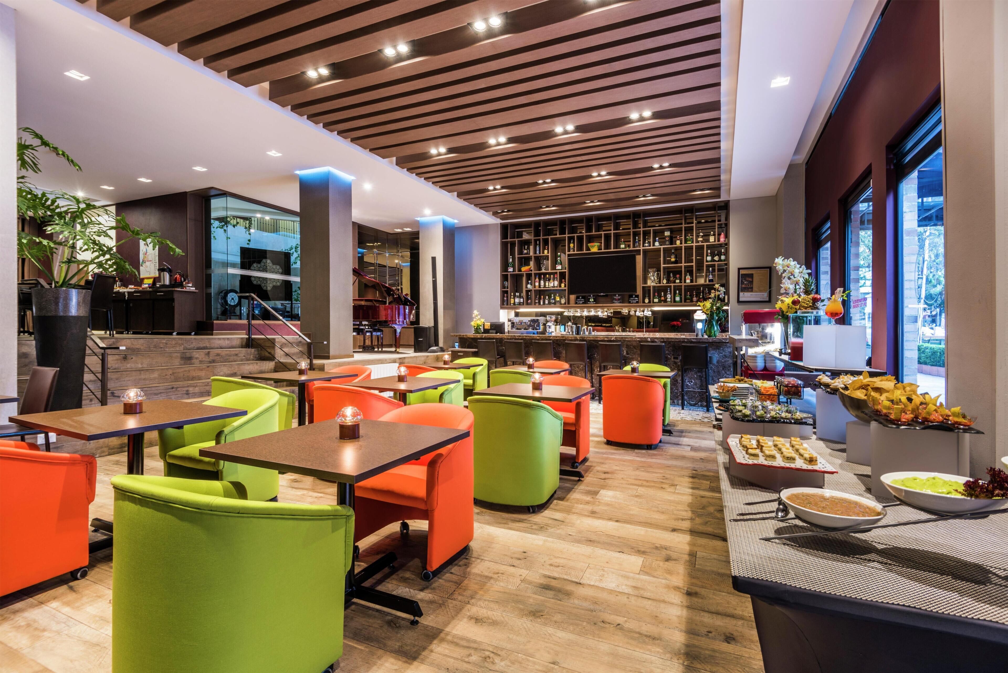 Un restaurant moderne avec des sièges aux couleurs vives, un bar et un choix varié de plats.