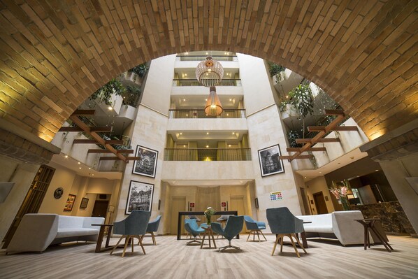 A hotel lobby with a central seating area, multiple floors, and a brick ceiling.