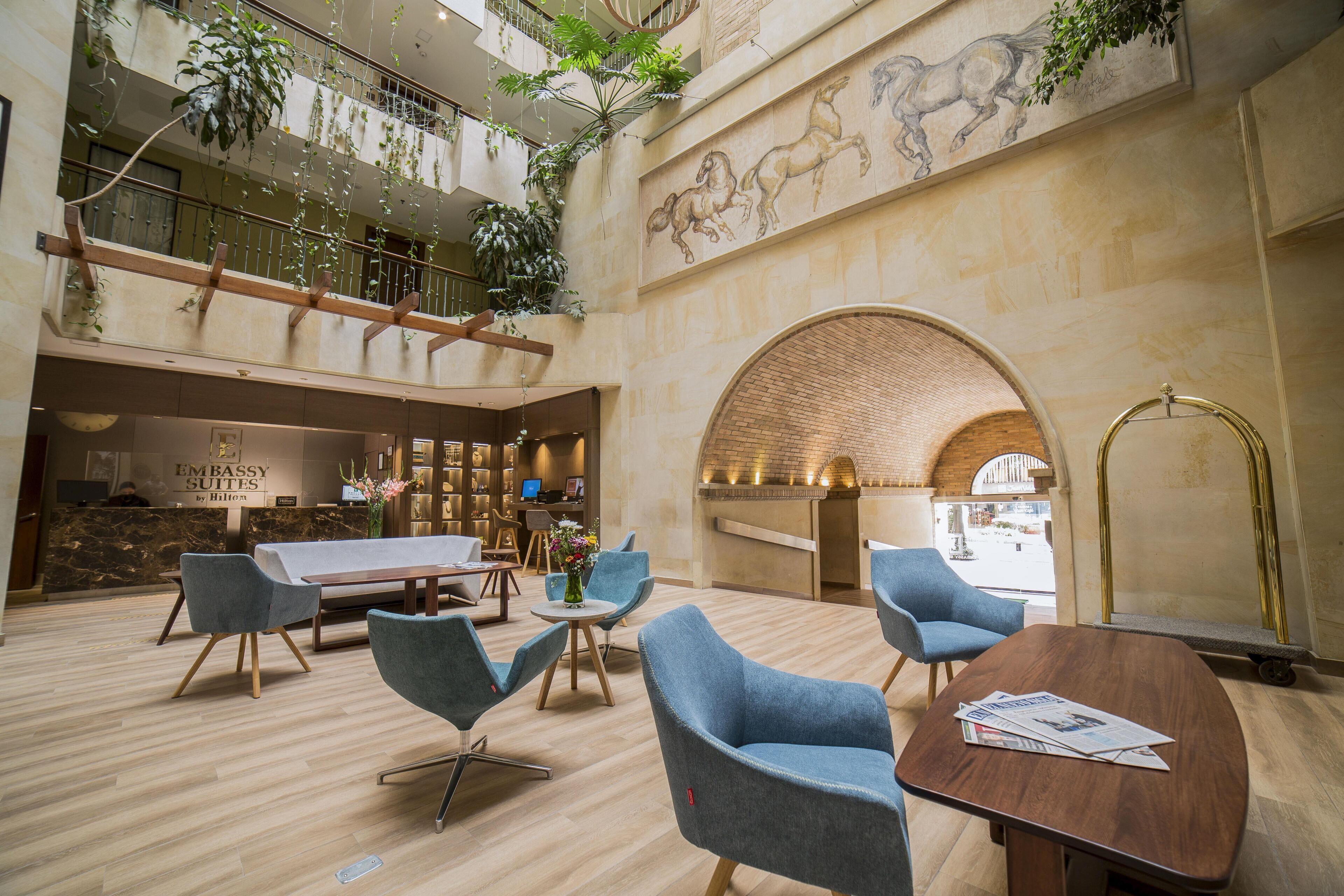 A hotel lobby with a reception desk, seating area, and a mural.