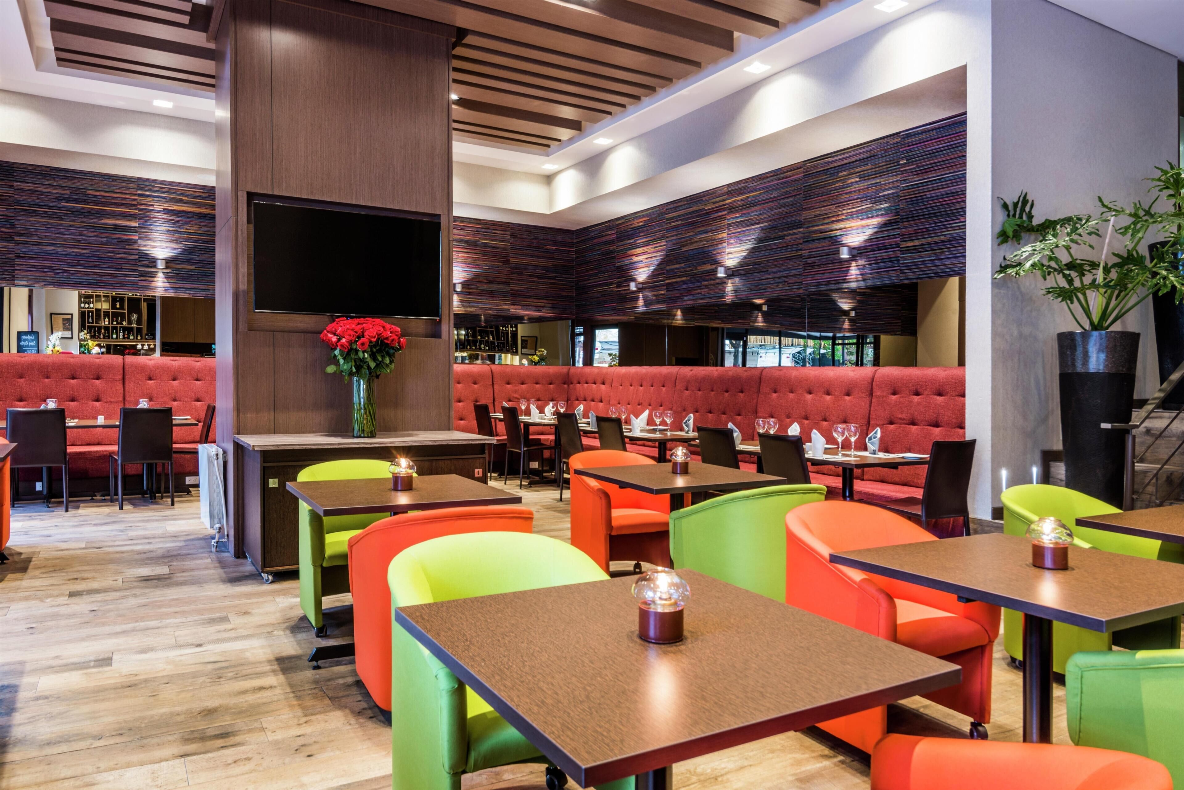 Un restaurante con cabinas, mesas y una zona de bar.