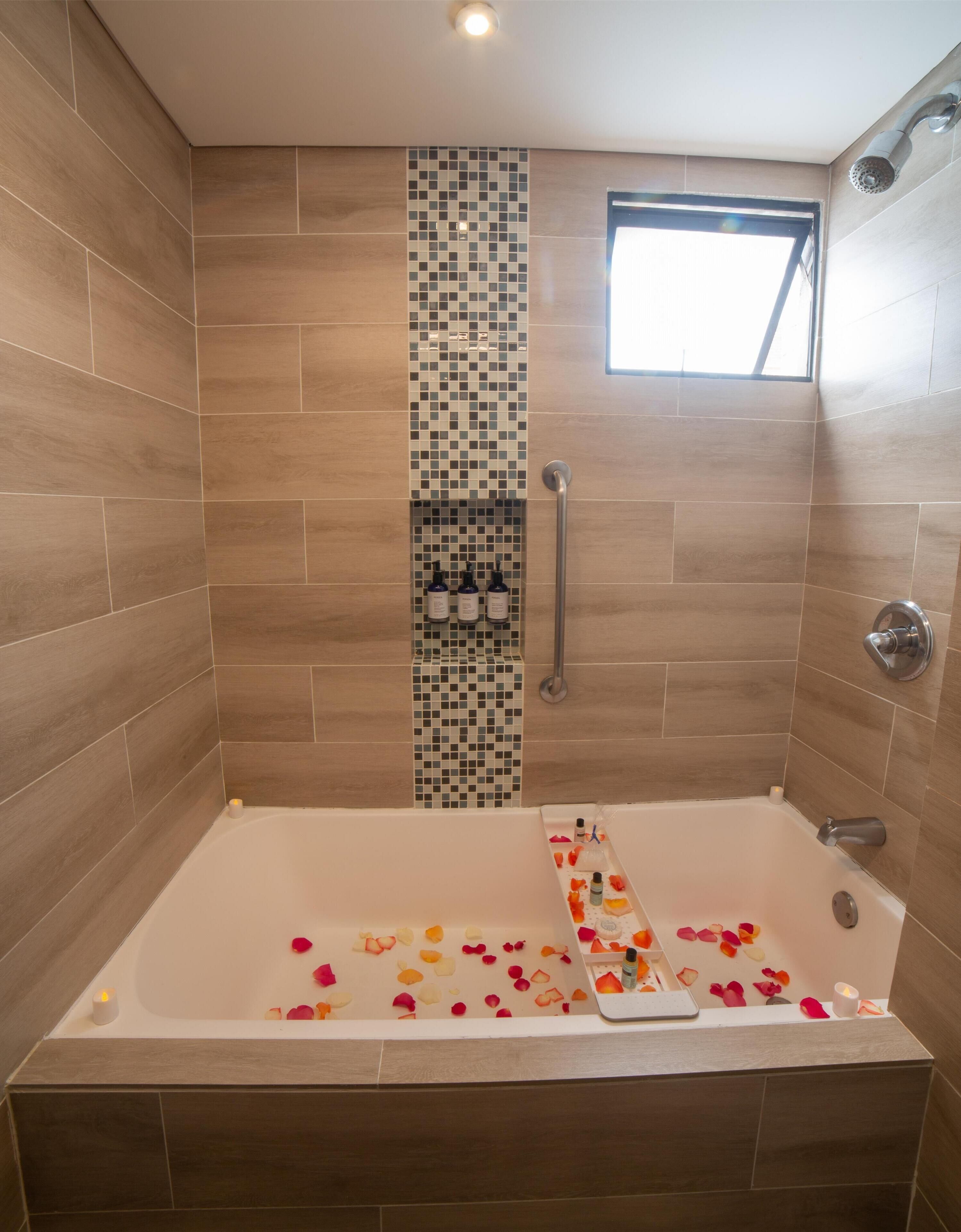 Un baño moderno con una bañera grande, ducha y una ventana pequeña.