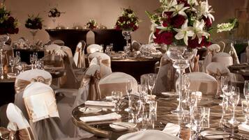 Una elegante disposición para el comedor con mesas redondas, sillas adornadas con cintas de satén y centros de mesa florales.