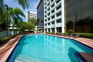 Una piscina al aire libre, sombrillas, sillones reclinables de piscina