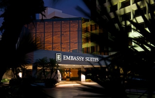 Fachada moderna de vidrio y entrada iluminada del hotel Embassy Suites.