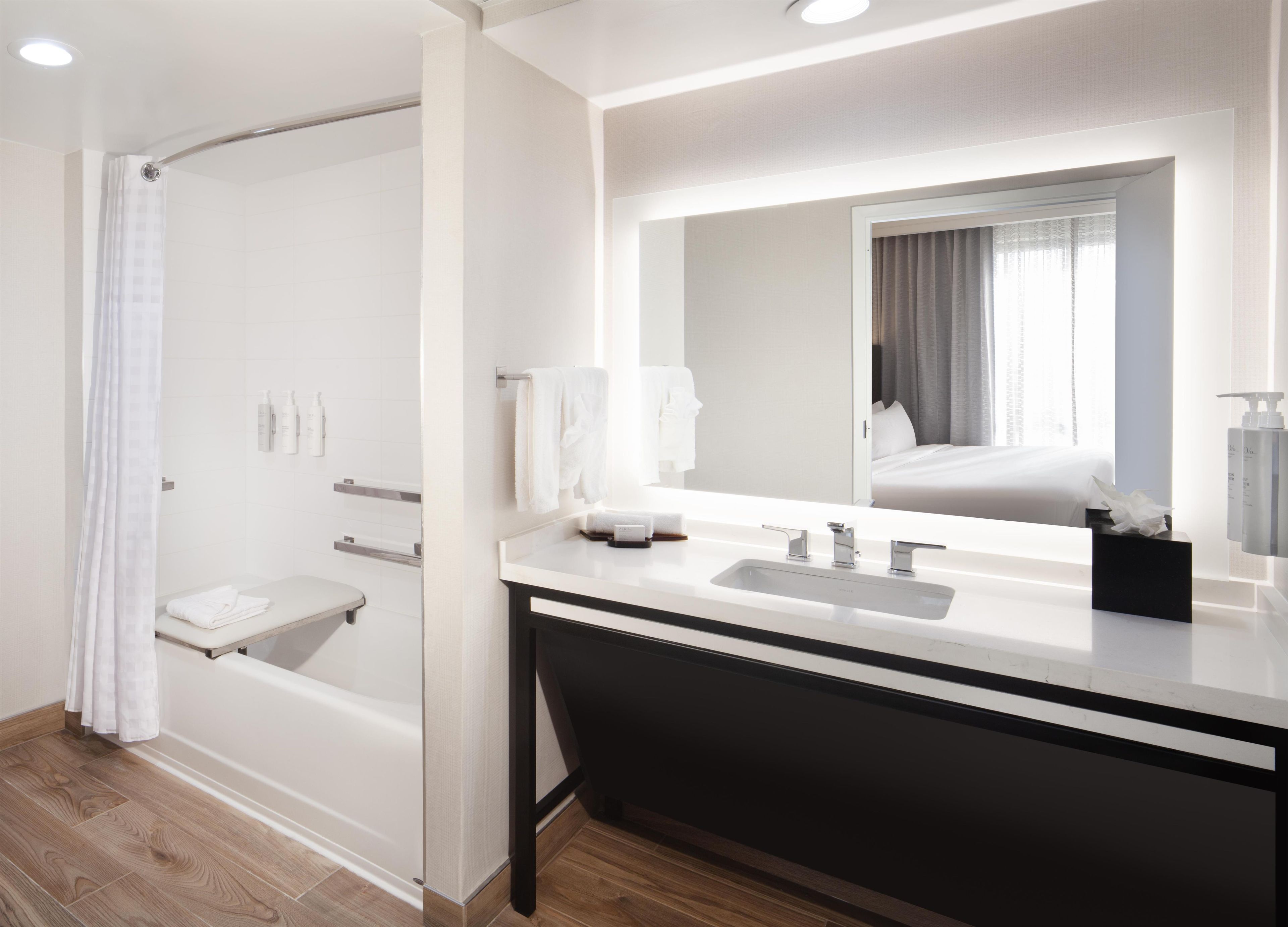 A modern bathroom with a bathtub, a vanity with a mirror, and a shower area.