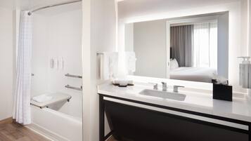 A modern bathroom with a bathtub, a vanity with a mirror, and a shower area.