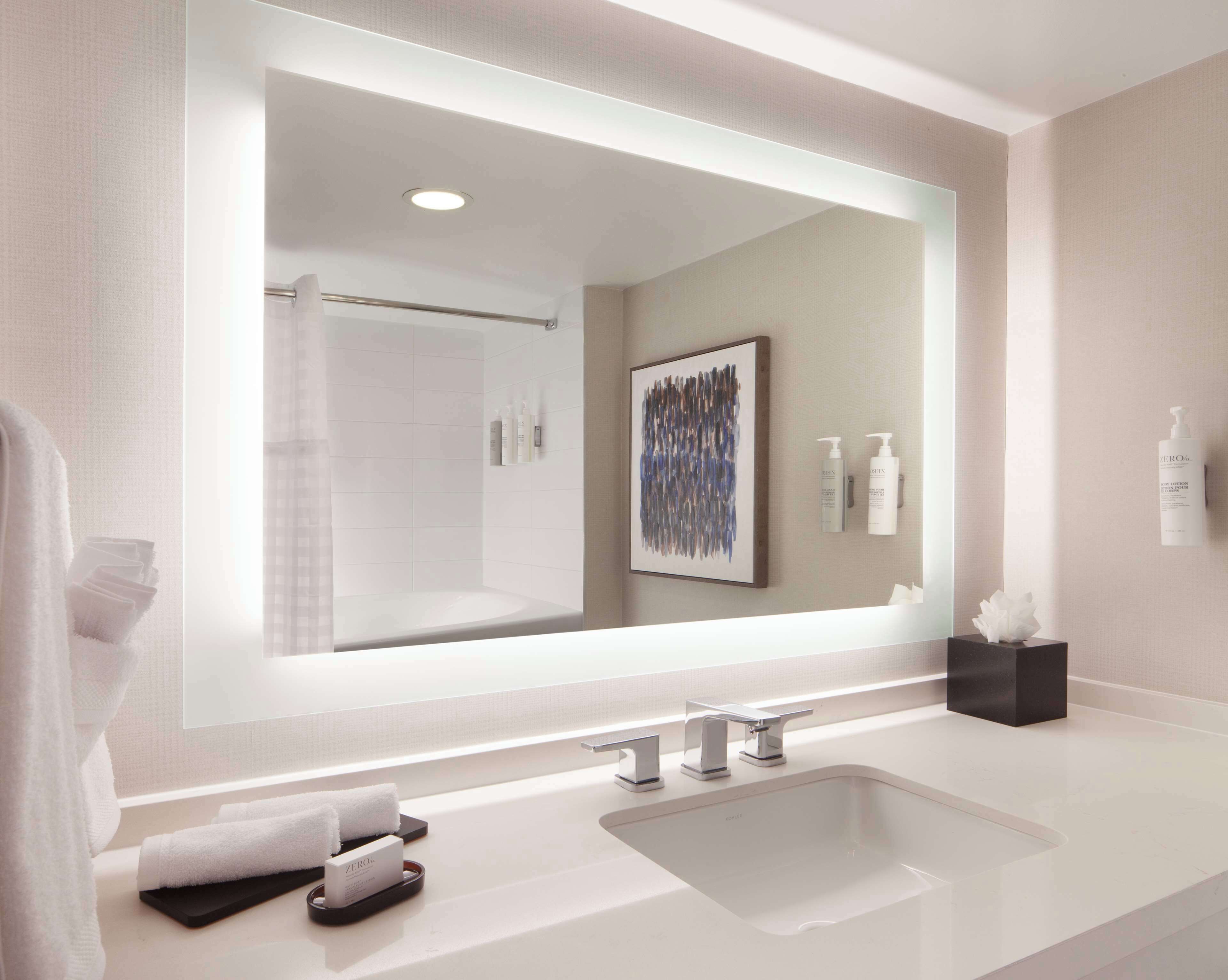 Un baño moderno con un espejo grande, un lavabo blanco y una zona de ducha.