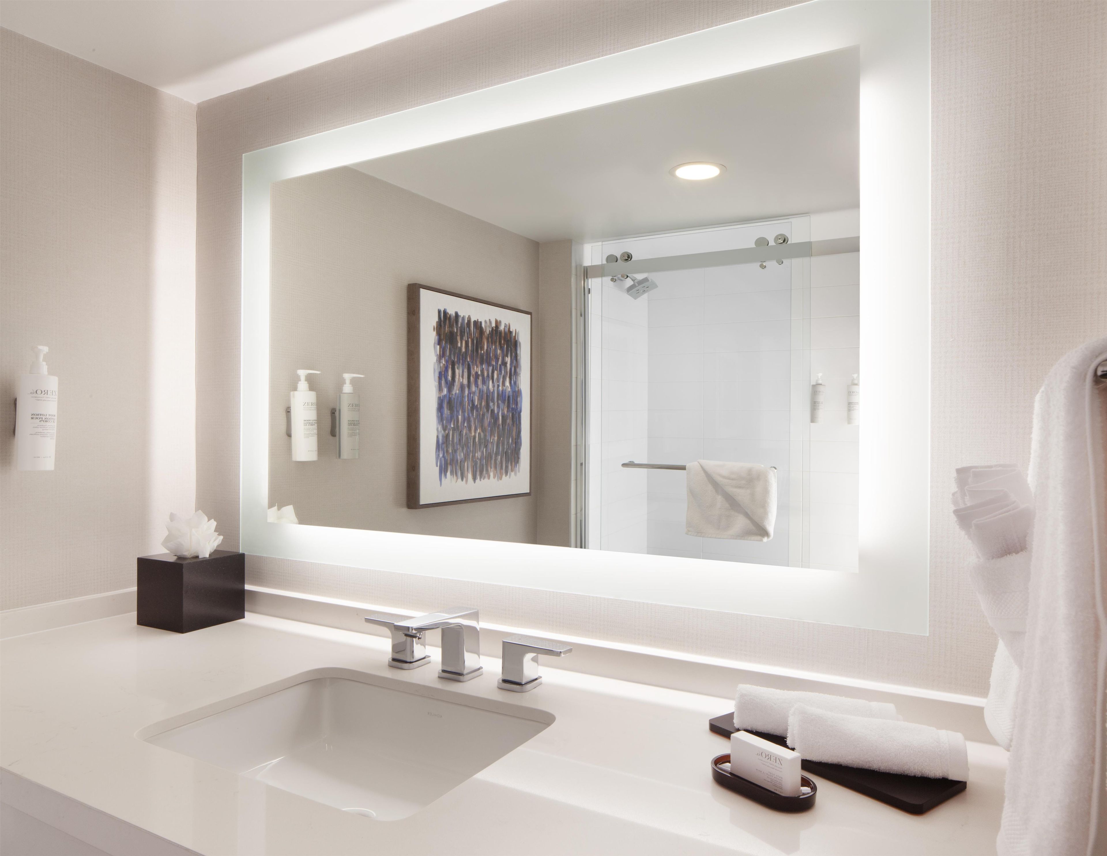 Een moderne badkamer met een grote spiegel, een wastafel en een douche.