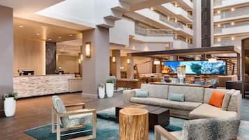 A spacious lobby with a reception desk, seating area, and a large TV screen.