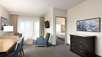 A hotel room with a dining table, a sofa, a chair, a dresser, and a bed.