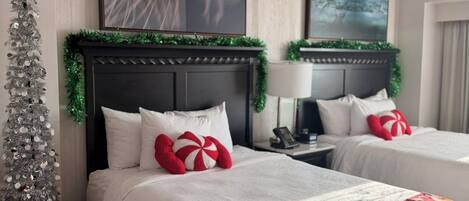 A hotel room with two beds, a Christmas tree, and holiday decorations.
