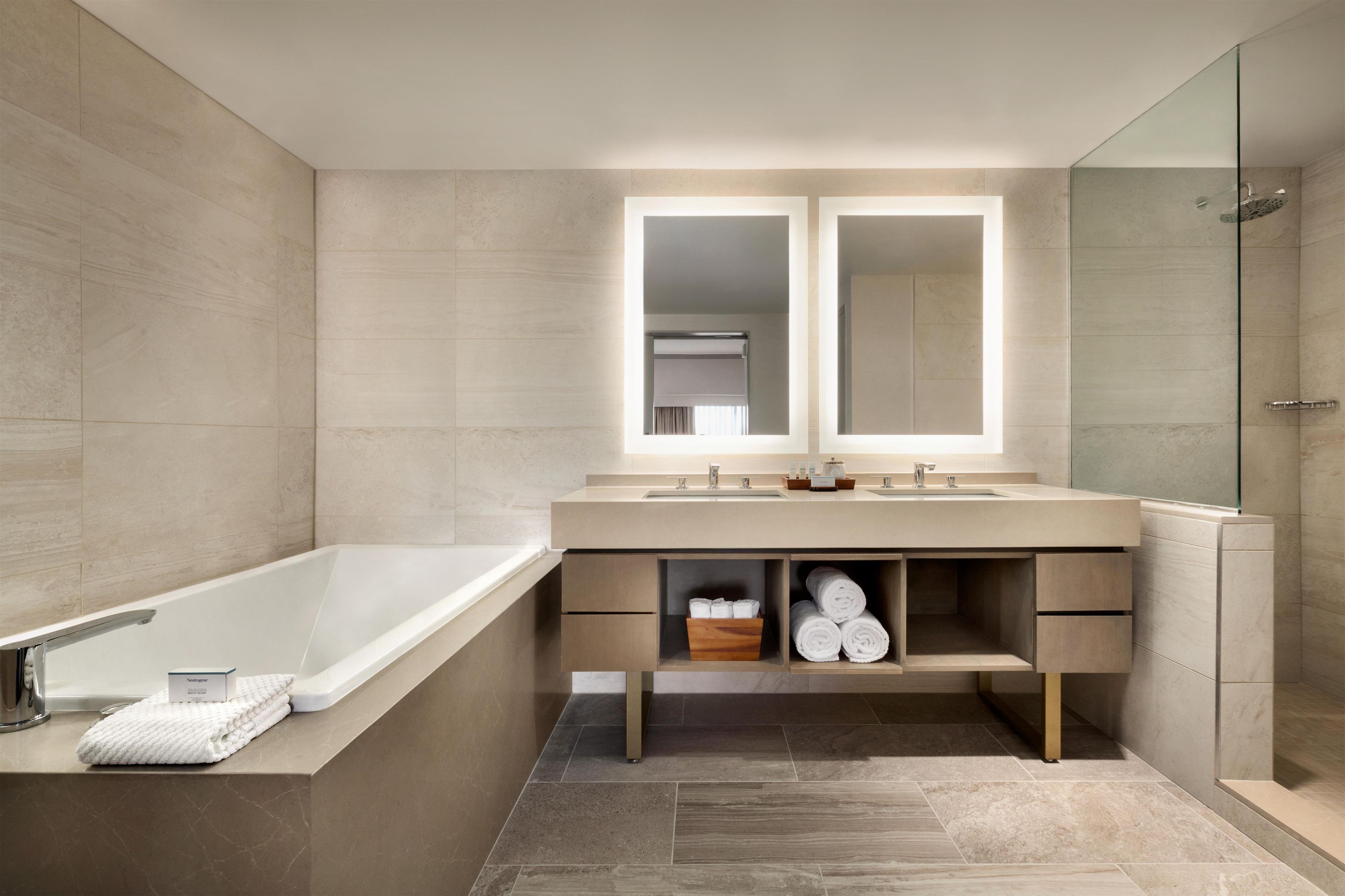 Ein modernes Badezimmer mit Badewanne, doppelter Waschtisch und einer Duschkabine aus Glas.