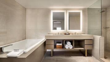A modern bathroom with a bathtub, a double sink vanity, and a glass shower enclosure.