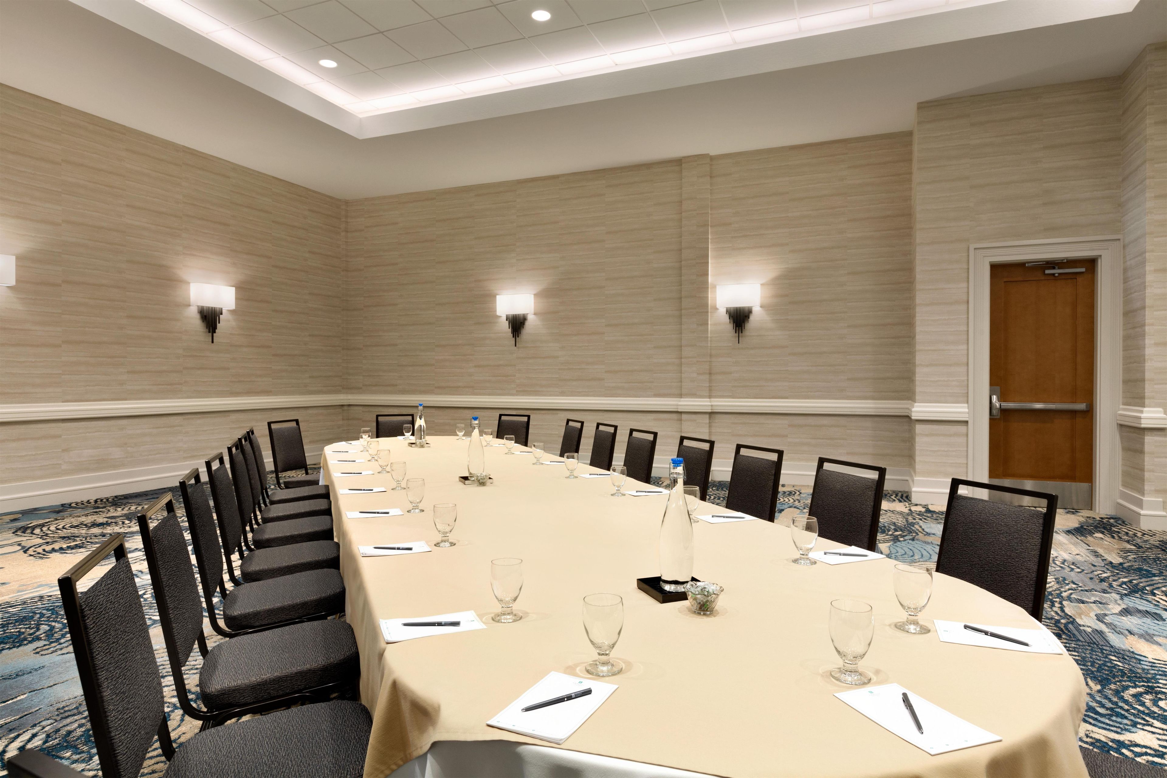 A conference room with a long table, chairs, and wall-mounted lighting.