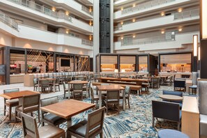 A multi-level hotel lobby with seating areas, a bar, and a staircase. - Embassy Suites by Hilton Monterey Bay Seaside (Seaside)