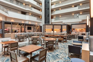 Un hall de hotel de varios niveles con áreas de descanso, un bar y una escalera.