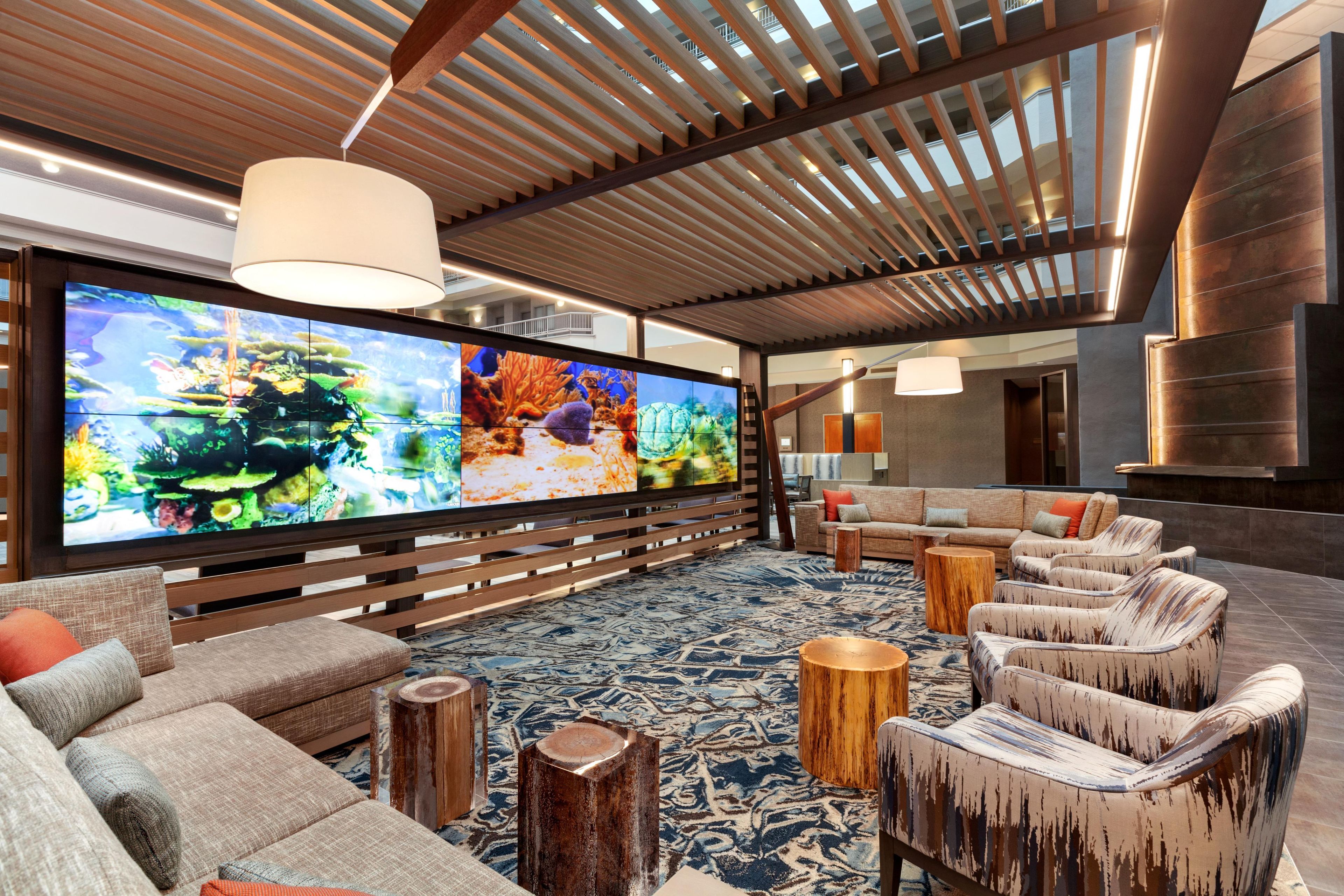 A modern living room with a large flat-screen TV, comfortable seating, and a wooden ceiling structure.